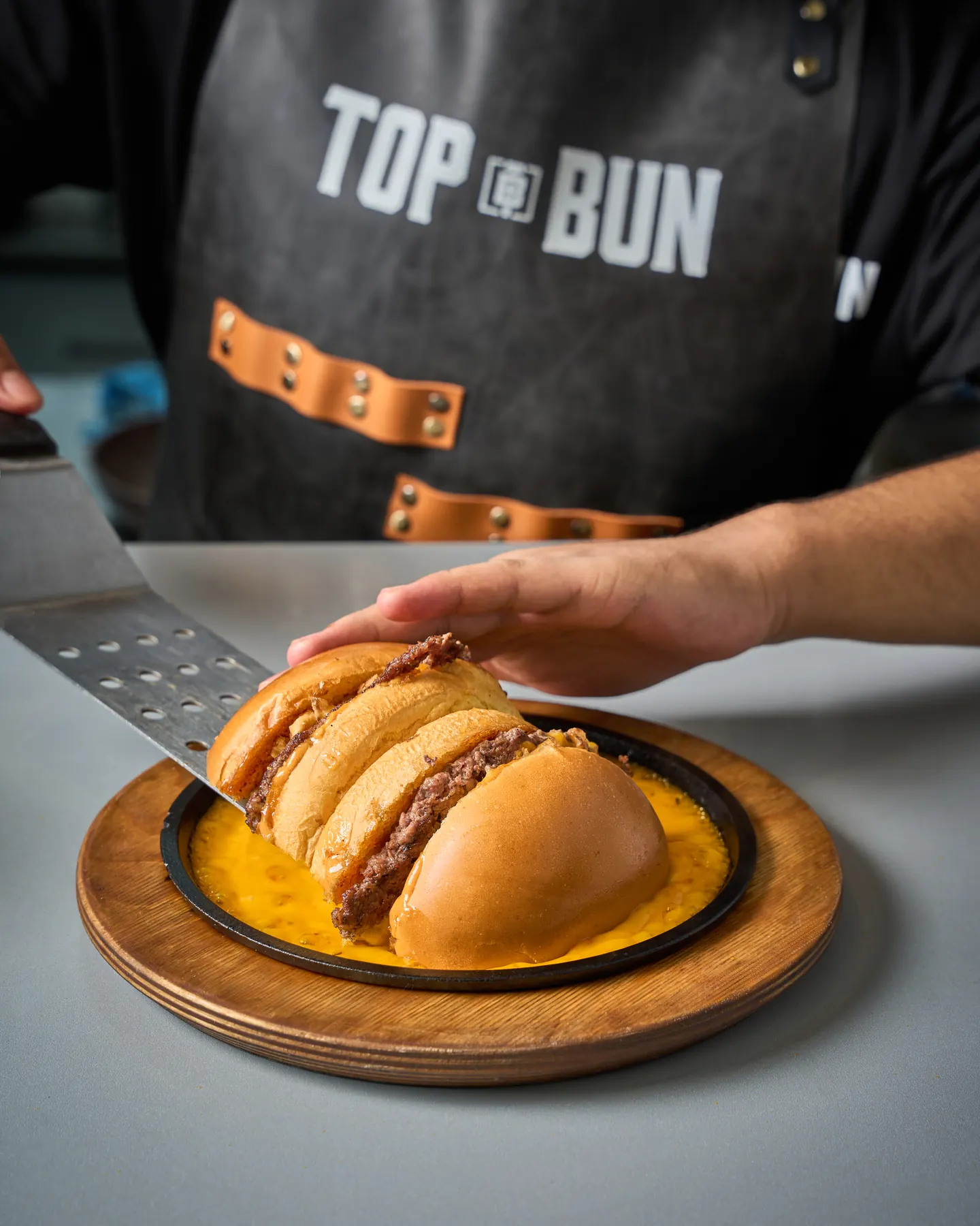 A Top Bun team member serving smash burgers at the pass